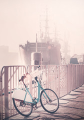 Vintage toned bicycle parked by pier with ship in a distance, Szczecin, Poalnd.