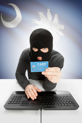 Hacker holding credit card with US state flag on background - South Carolina
