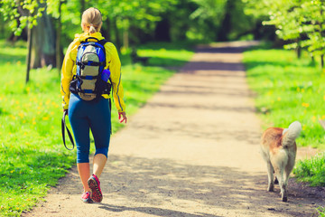 Woman runner walking with dog in summer park