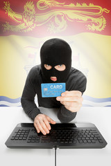 Hacker with credit card in hand and Canadian province flag on background - New Brunswick