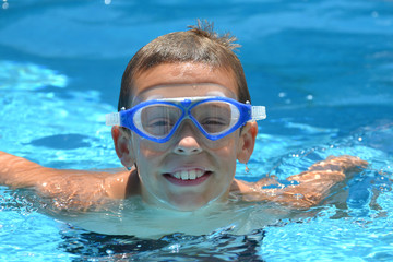 boy with goggles in swimming pool having fun