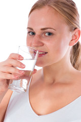 Portrait of a young happy girl drinking water from glass after fitness, isolated on a white background
