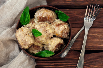 meatballs with basil cream sauce on the old wooden background in a clay bowl. Rural or rustic style. top view. Copy space. free text space. close up