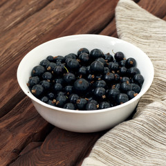 Honeysuckle berries in a deep ceramic bowl on a wooden background. Fresh ripe blueberries. Top view with copy space for text