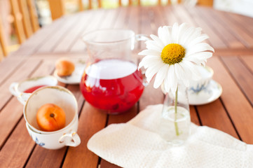 Fruit drink with flower on wooden table outdoors. Focus on flower. Healthy eating