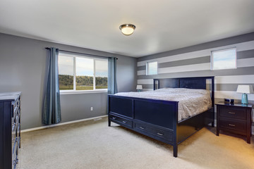 Beautifully modern master bedroom with gray stripped wall.