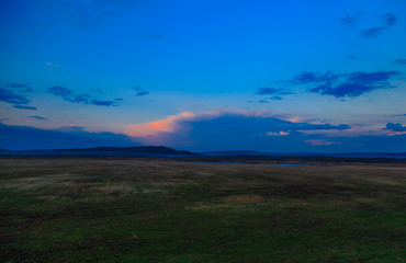 sunset blue sky over hills and field