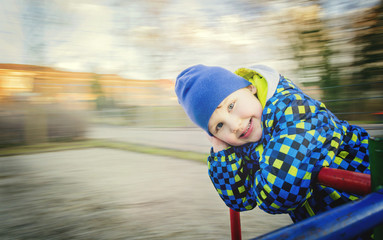 Boy posing on the carousel in motion.
