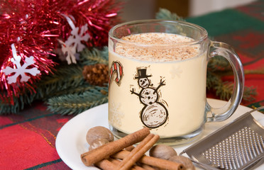 Christmas Eggnog – Eggnog in a holiday cup. Cinnamon and nutmeg in foreground. 