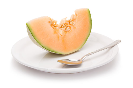 Cantaloupe Slice – A slice of fresh cantaloupe on a white plate. On a white background.
