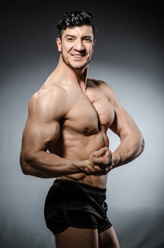 Muscular man posing in dark studio