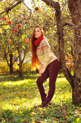 Young redheaded woman with long straight hair in the apple garden