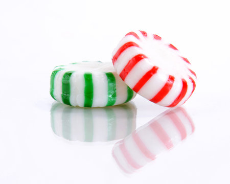 Red and Green Peppermint Candies on a Reflective White Background