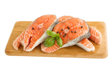 Raw salmon fish steaks with fresh herbs on cutting board isolated over white