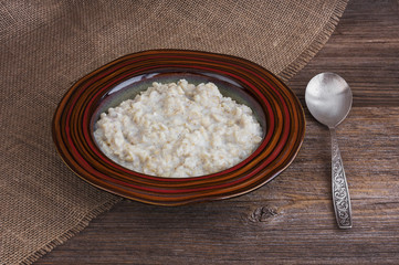 Oatmeal porridge in plate on wooden table