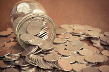 Coins spilling out of a glass bottle with filter effect retro vi