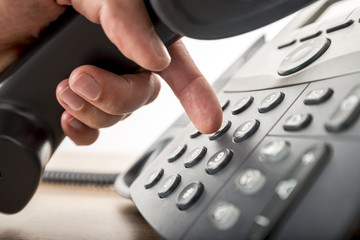 Closeup of dialing a telephone number on a black landline teleph