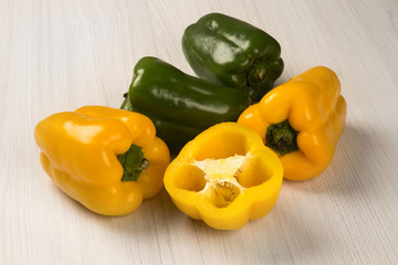 Some red, green and yellow peppers over a wooden surface