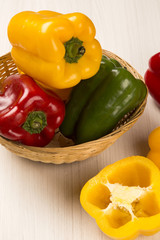Some red, green and yellow peppers over a wooden surface