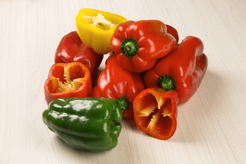 Some red, green and yellow peppers over a wooden surface