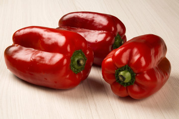 Some red, green and yellow peppers over a wooden surface