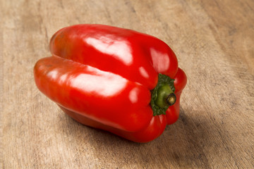 Some red, green and yellow peppers over a wooden surface
