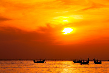Fototapeta premium silhouette of fishermen boats fishing in sunset at the beach.