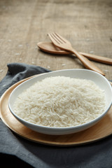 Close-up view of uncooked white rice with napery and wooden spoo