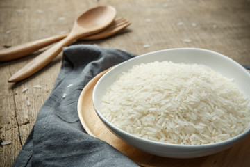 Dry rice grains with wooden spoon on wooden table - soft focus