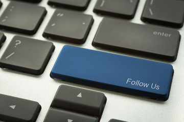 Laptop keyboard with typographic FOLLOW US button