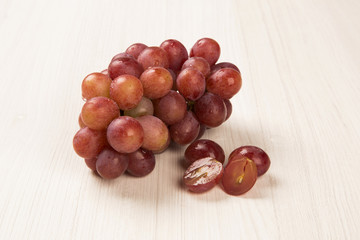 Some red grapes in a wooden pot over a wooden surface seen from