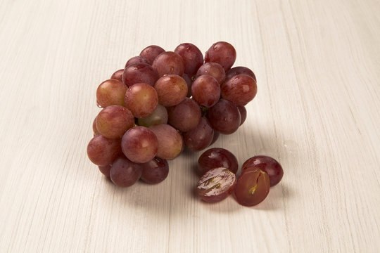 Some red grapes in a wooden pot over a wooden surface seen from