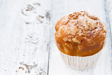 Apple muffin with icing sugar on white wooden background