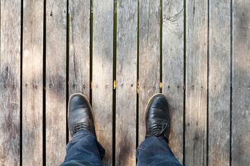 two legs wearing moccasins  and denim jeans on wooden background