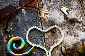 glasses, earrings with feathers, Dreamcatcher, jewelry, beads in the shape of a heart on a wooden background