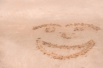 Handwrite face on the sand at the beach