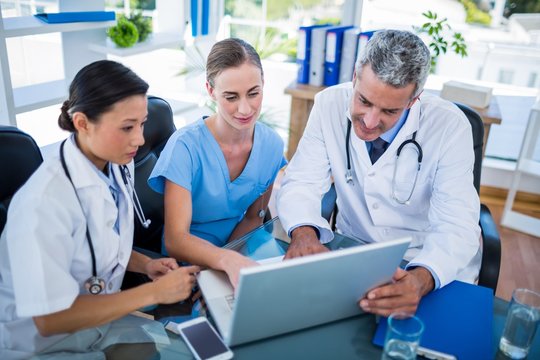 Doctors and nurse looking at laptop 