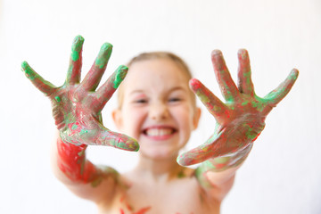 Little girl showing her hands, covered in finger paint