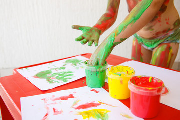 Child dipping fingers in washable finger paints