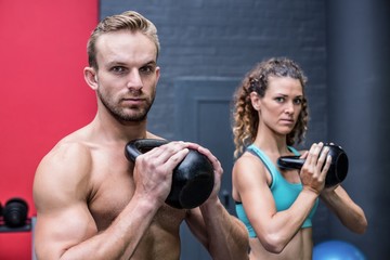 Fototapeta na wymiar Muscular couple exercising with kettlebells