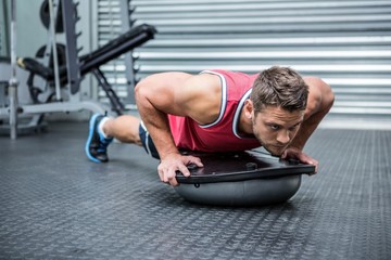 Naklejka premium Muscular man using bosu ball