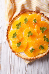 Orange tart with white cream and mint close-up. vertical top view
