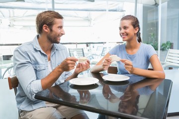 Young happy couple eating cake together