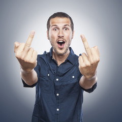handsome young man showing middle finger, insult sign with funny