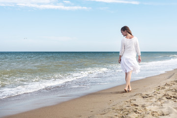 Fototapeta na wymiar Woman in summer dress standing on a sea