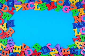 Frame of plastic colorful alphabet letters on a blue