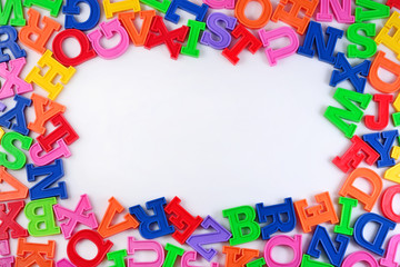 Fototapeta na wymiar Frame of plastic colorful alphabet letters on a white