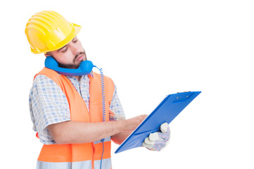 Busy builder using phone while holding clipboard