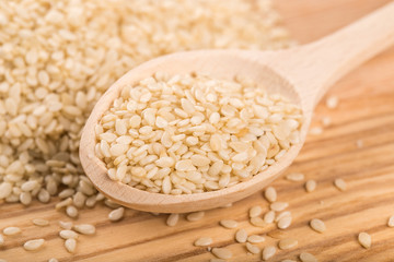 Organic natural sesame seeds in the wooden spoon on wood table