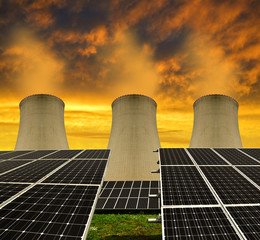 Solar energy panels before a nuclear power plant at sunset